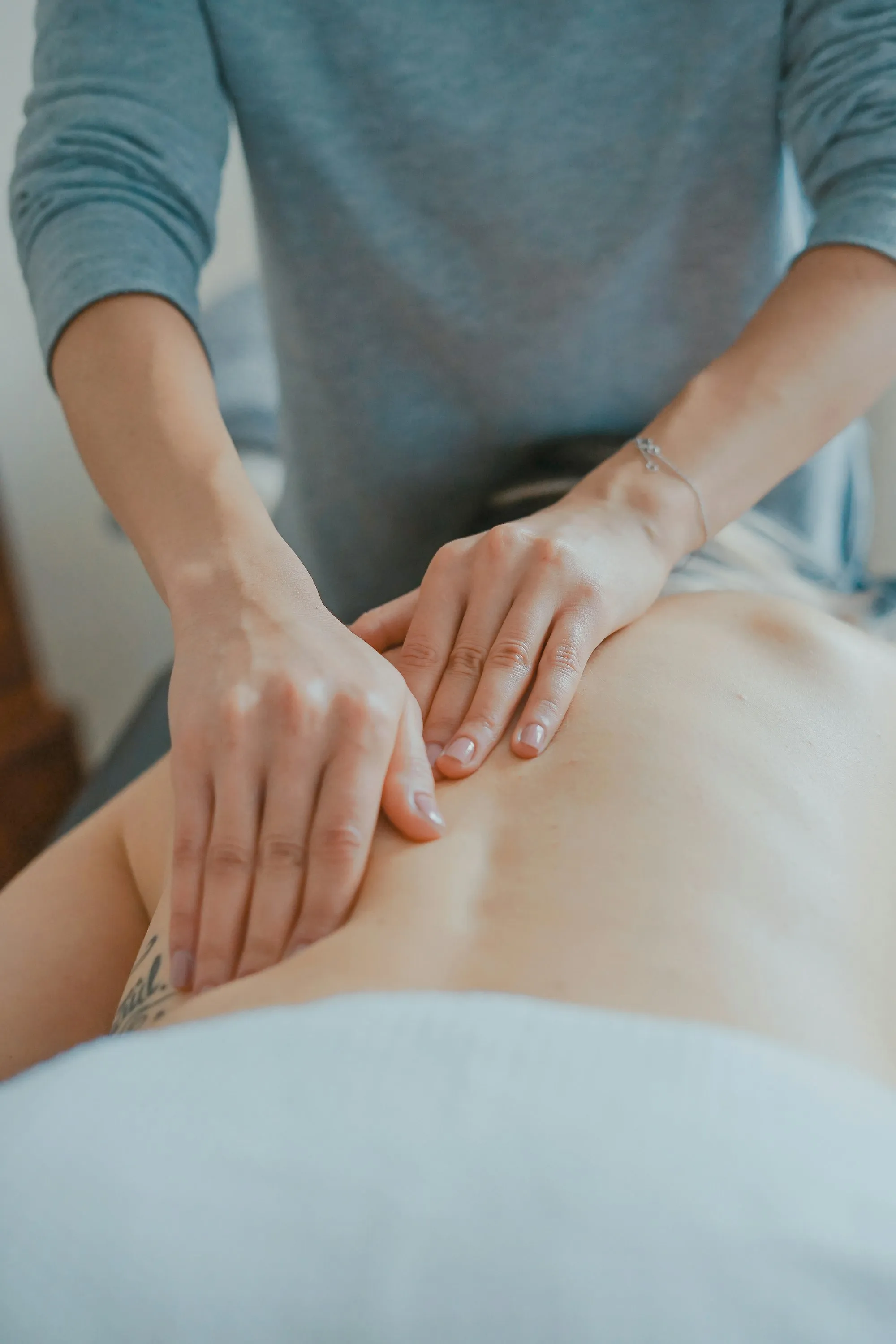 A practitioner’s hands during a body treatment in warm, natural light
