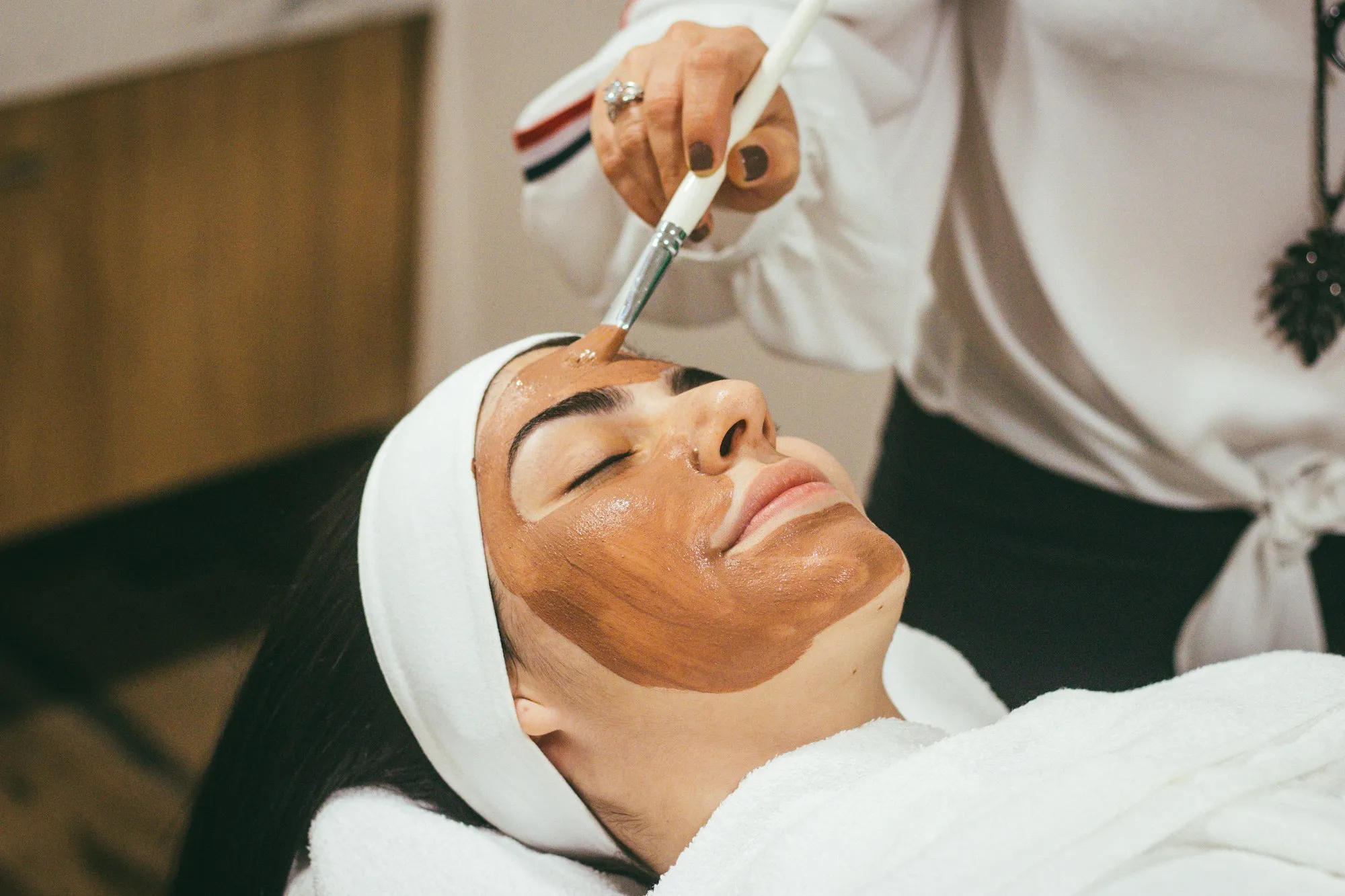 Esthetician applying a face mask during a treatment